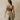 Woman wearing a gray sports bra and beige linen pants against a beige wall