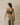 Woman wearing a gray sports bra and beige linen pants against a beige wall
