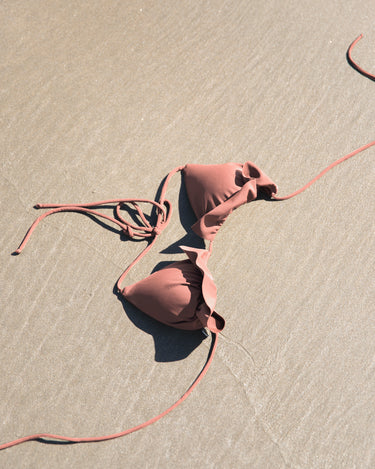 pink bikini top on sand
